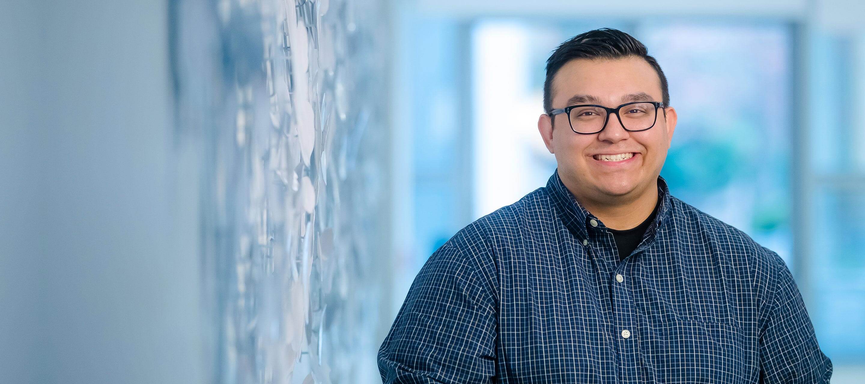 GDIT's Thomas L smiling next to blue wall (centered right)