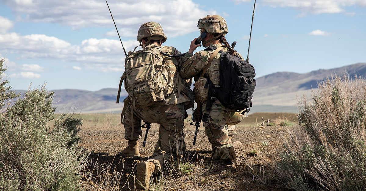 two soldiers kneeling in the field together