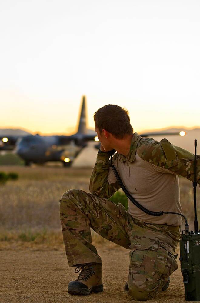 soldier on his knee, looking back at the airplane