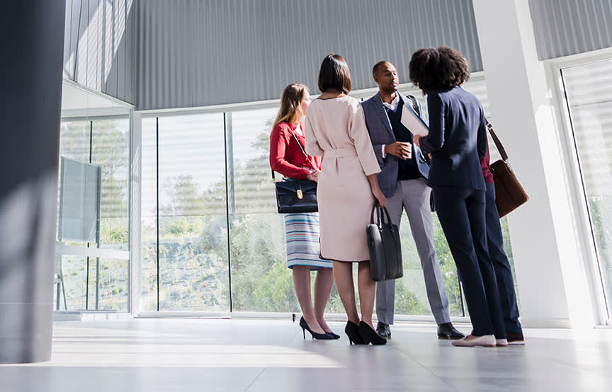 men and women standing in a circle talking in business attire