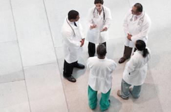 Men and women in lab coats standing in a circle talking