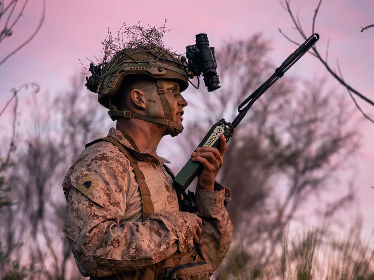 soldier holding a radio, pink sky behind him