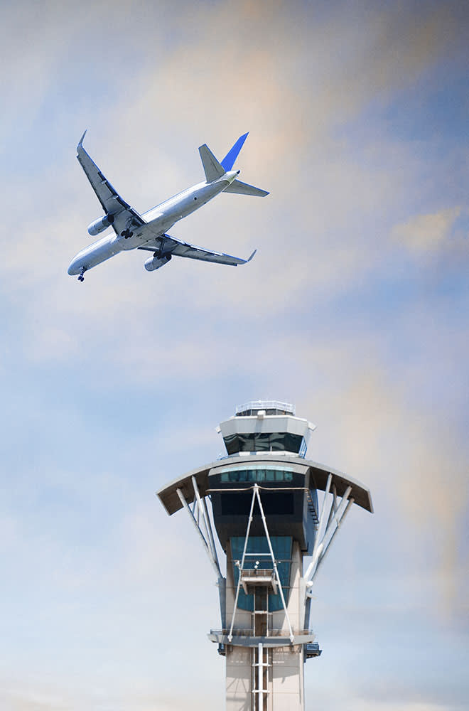 Airplane in the sky and an air traffic control tower.