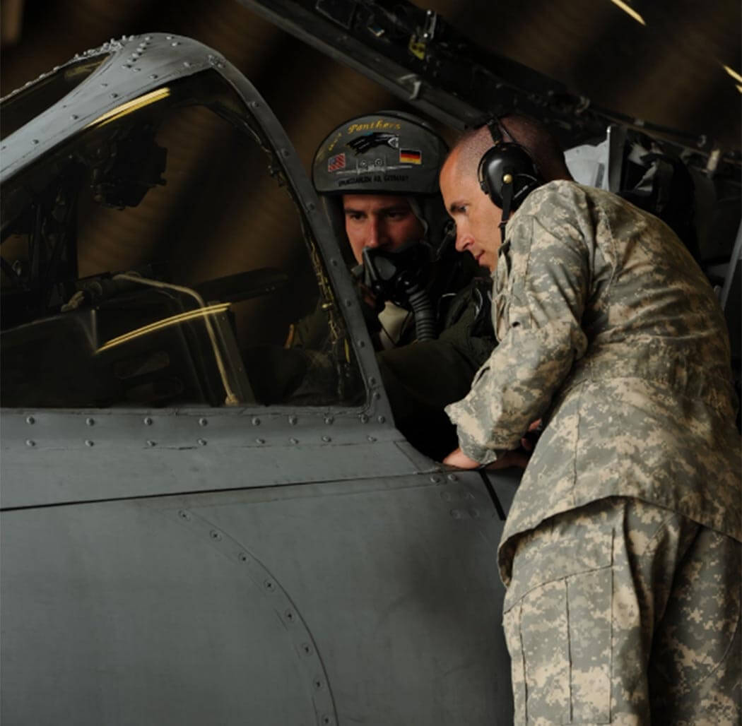 two soldiers looking at at a screen in a plane