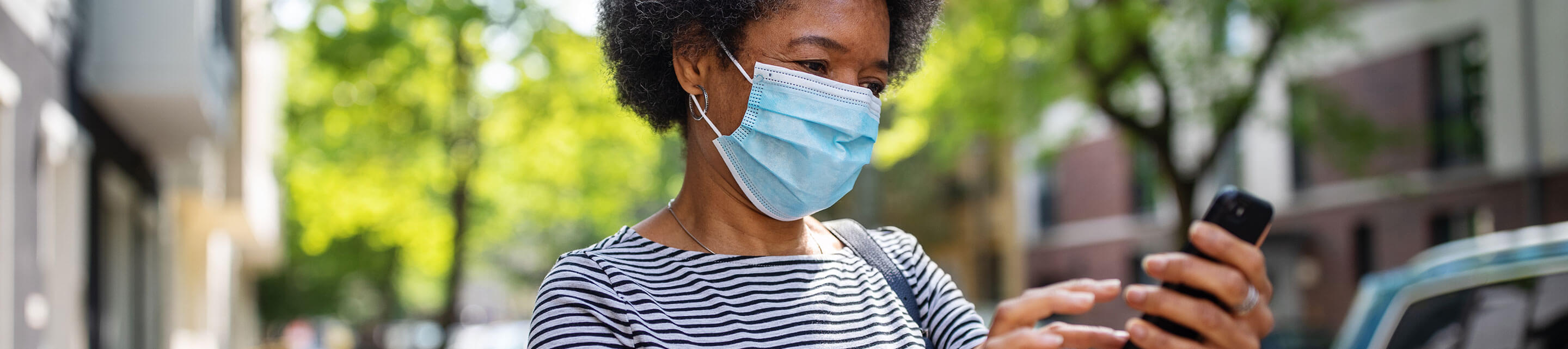 Person with face mask looking at cellphone 