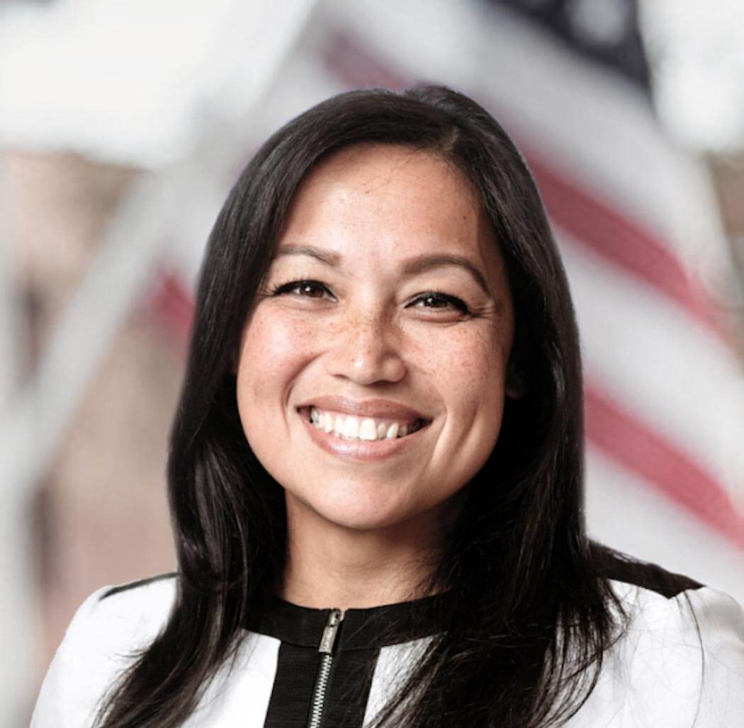 Person smiling with a US flag in the background.