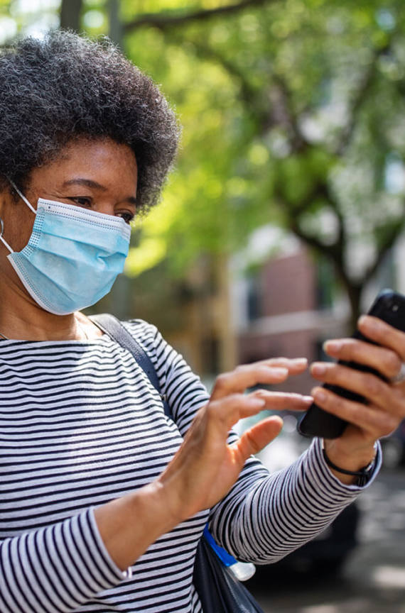 person with face mask looking at cell phone