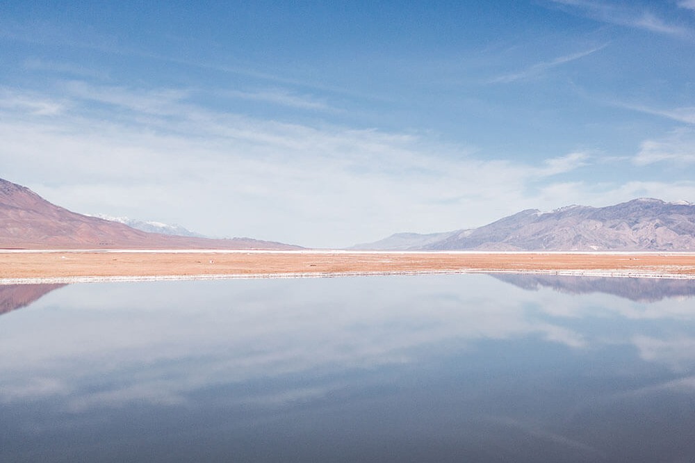 reflection of clouds in a body of water with hills in the background