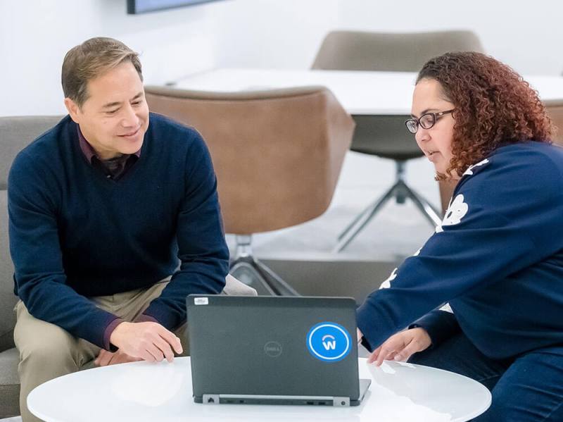 two people talking at a table and a laptop