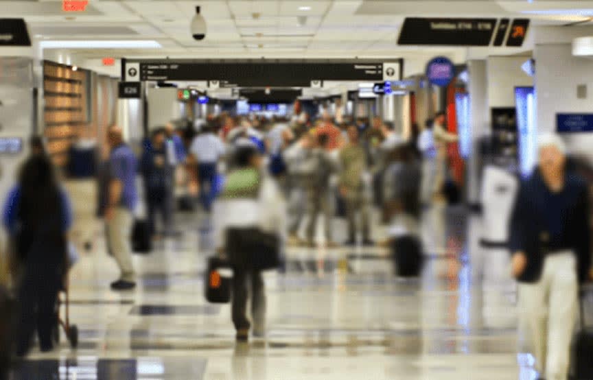 image of people moving throughout an airport, bodies blurred to show movement