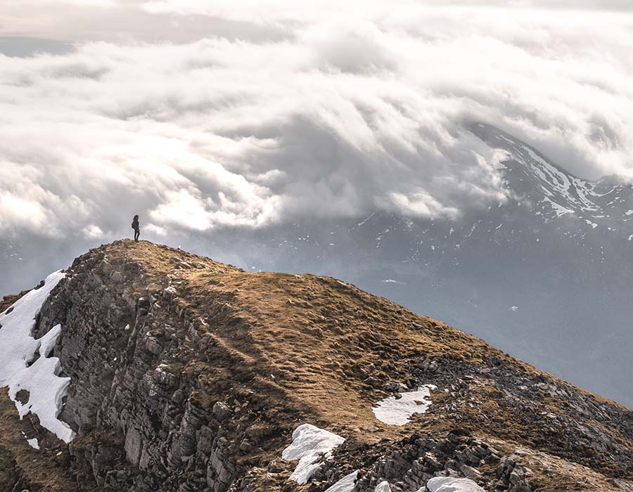 Man on top of mountain trail with clouds above
