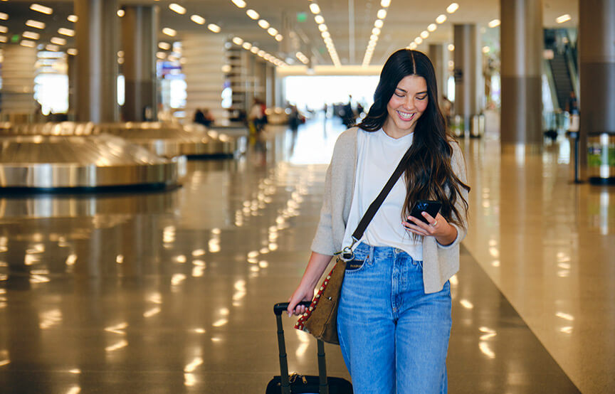 woman on her cellphone walking out of baggage claim in airport 