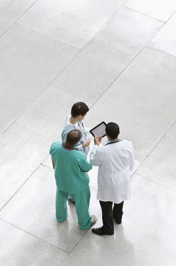 Group of doctors talking around a tablet.