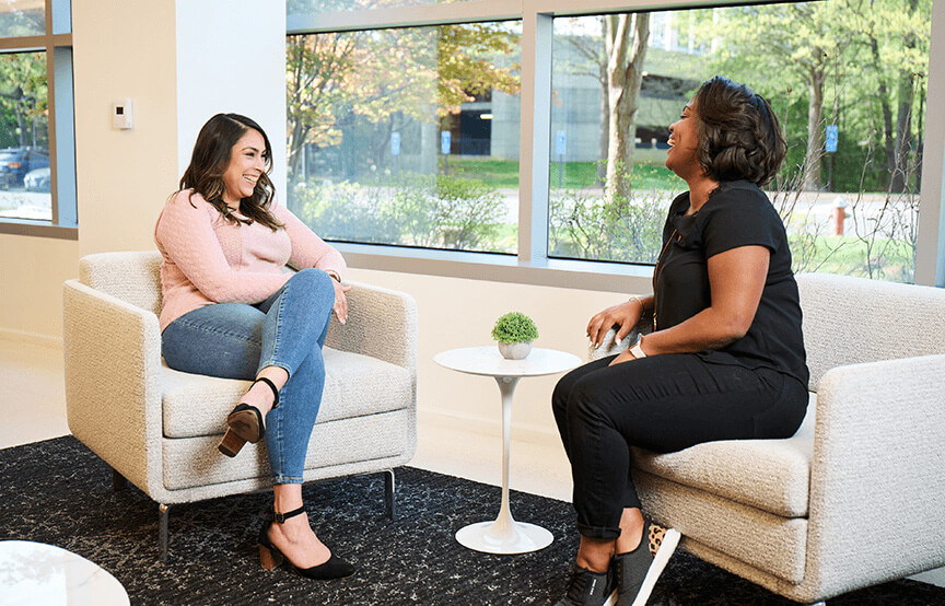 two woman talking to each other in chairs