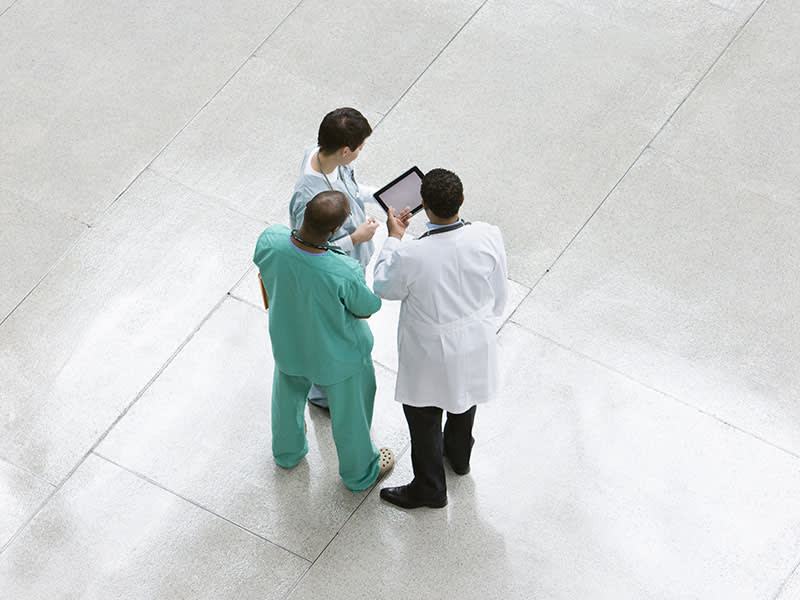 group of doctors talking around a tablet
