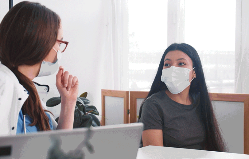 image shows a doctor talking to patient with mask
