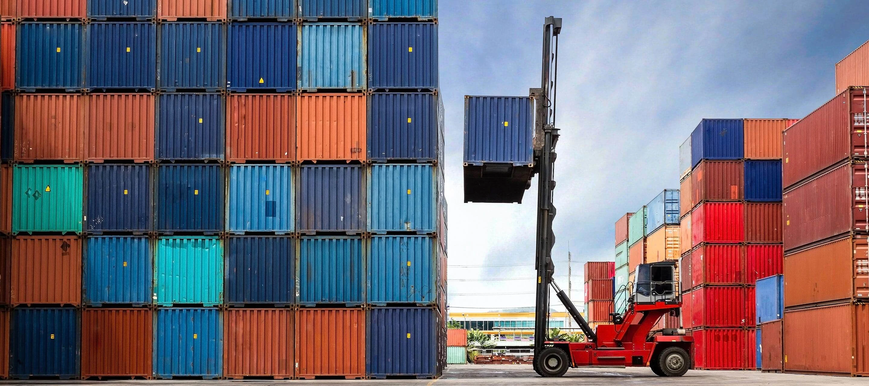 forklift surrounded by orange and blue shipping containers