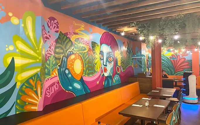 A brightly coloured hand-painted mural of a woman's face surrounded by flowers at Las Iguanas Elveden