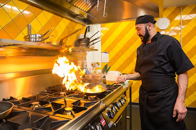 Chef cooking over a flaming grill