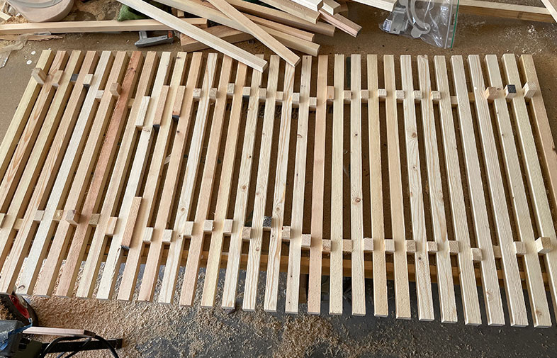 Rå träpanel med ljusa ribbor på verkstadsgolv med sågspån och träspill