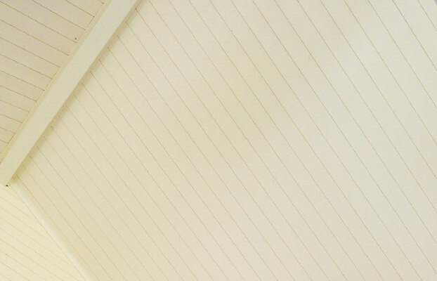 Vitt innertak med tunna träpaneler och en diagonal takbalk.