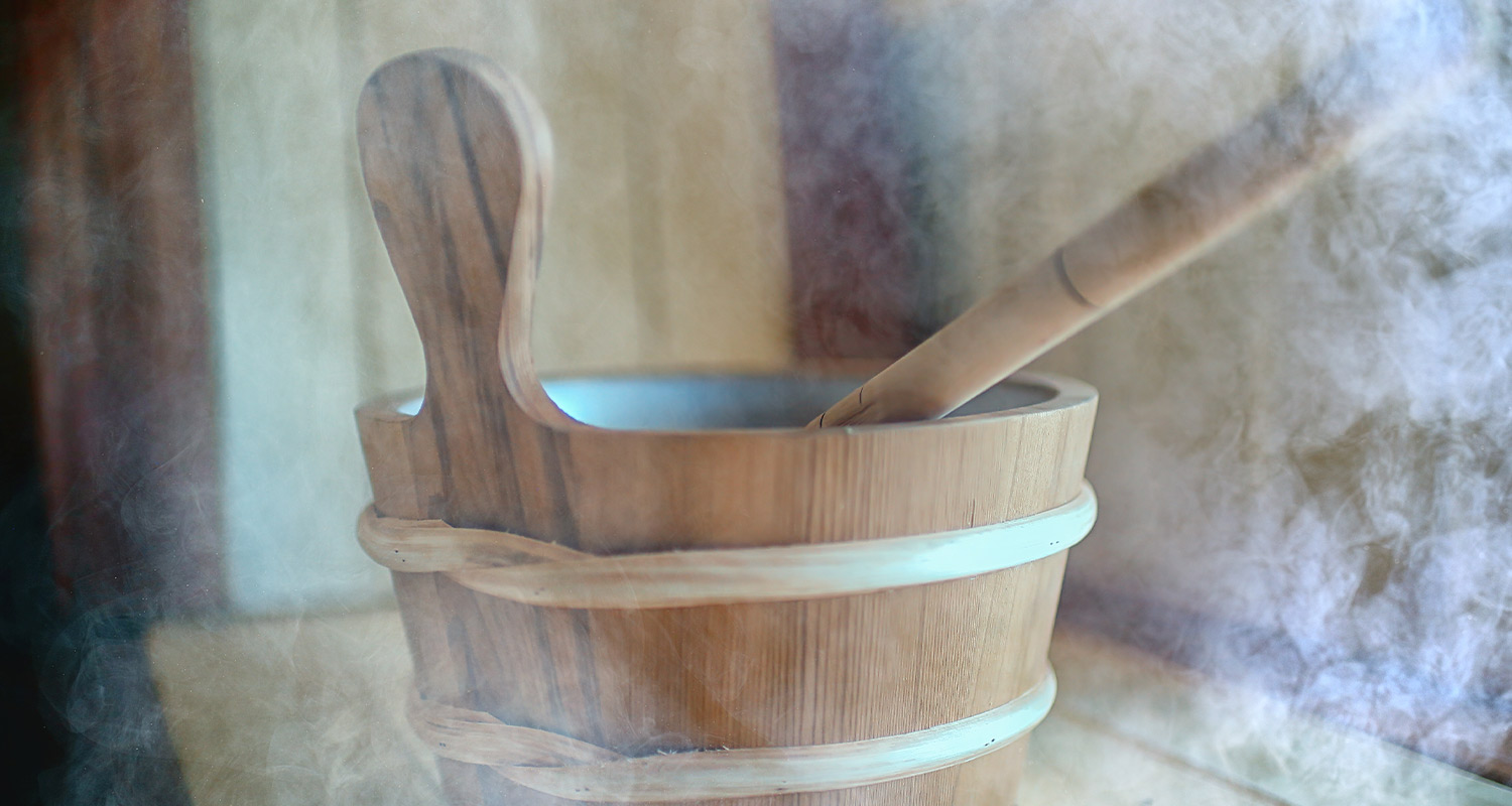 Ljus bastuhink i trä med skopa och ånga i varmt ljus