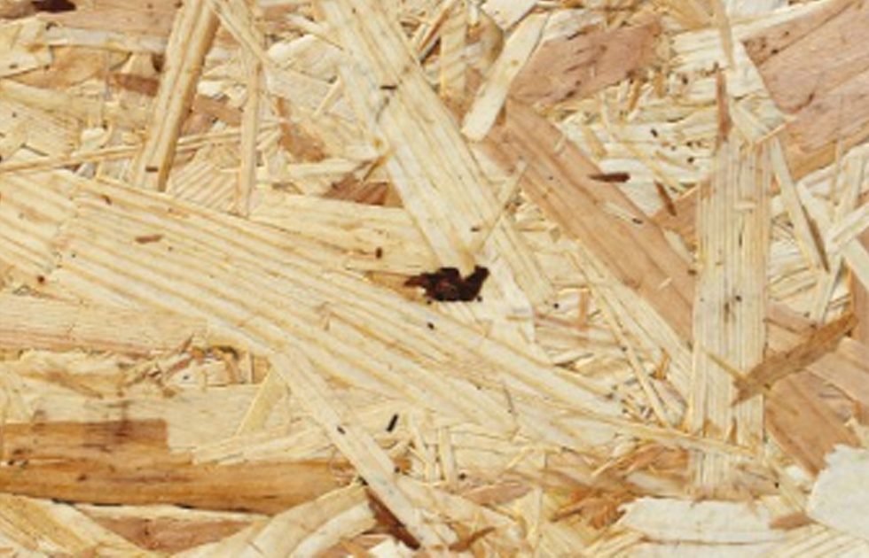 Närbild av ljusbeige spånskiva med sammanpressade träspån i olika riktningar.