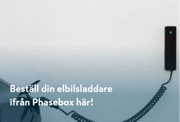Vit elbil laddas av svart Phasebox-laddare med spiralkabel mot vitblå vägg.