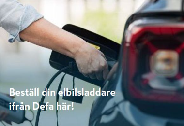 Hand håller grå elbilsladdare ansluten till mörkblå elbil vid utomhusladdstation