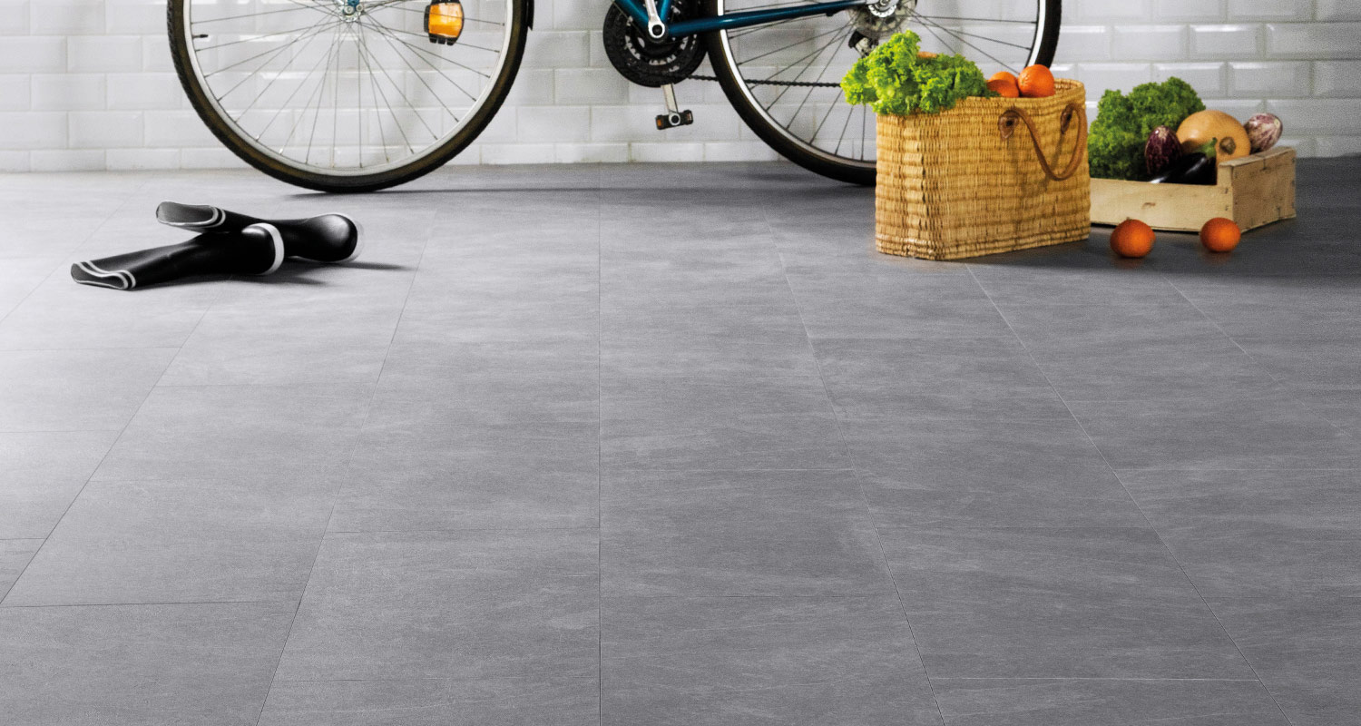 Cykelhjul mot vit kakelvägg, rullad yogamatta, korg och trälåda fyllda med grönsaker och apelsiner.