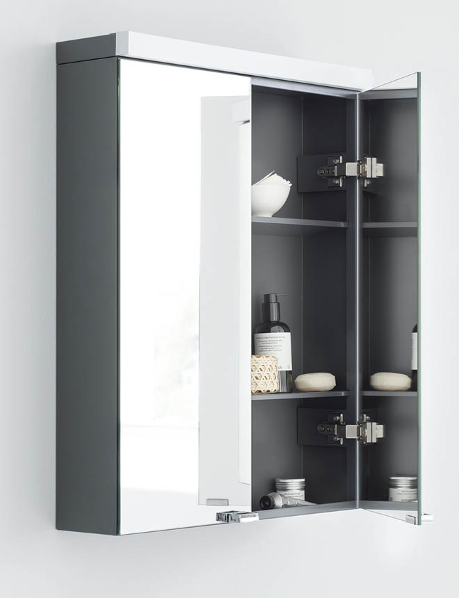 Modernt grått badrumsskåp med spegelyta, öppet dörr med mörkgrå hyllor och toalettartiklar
