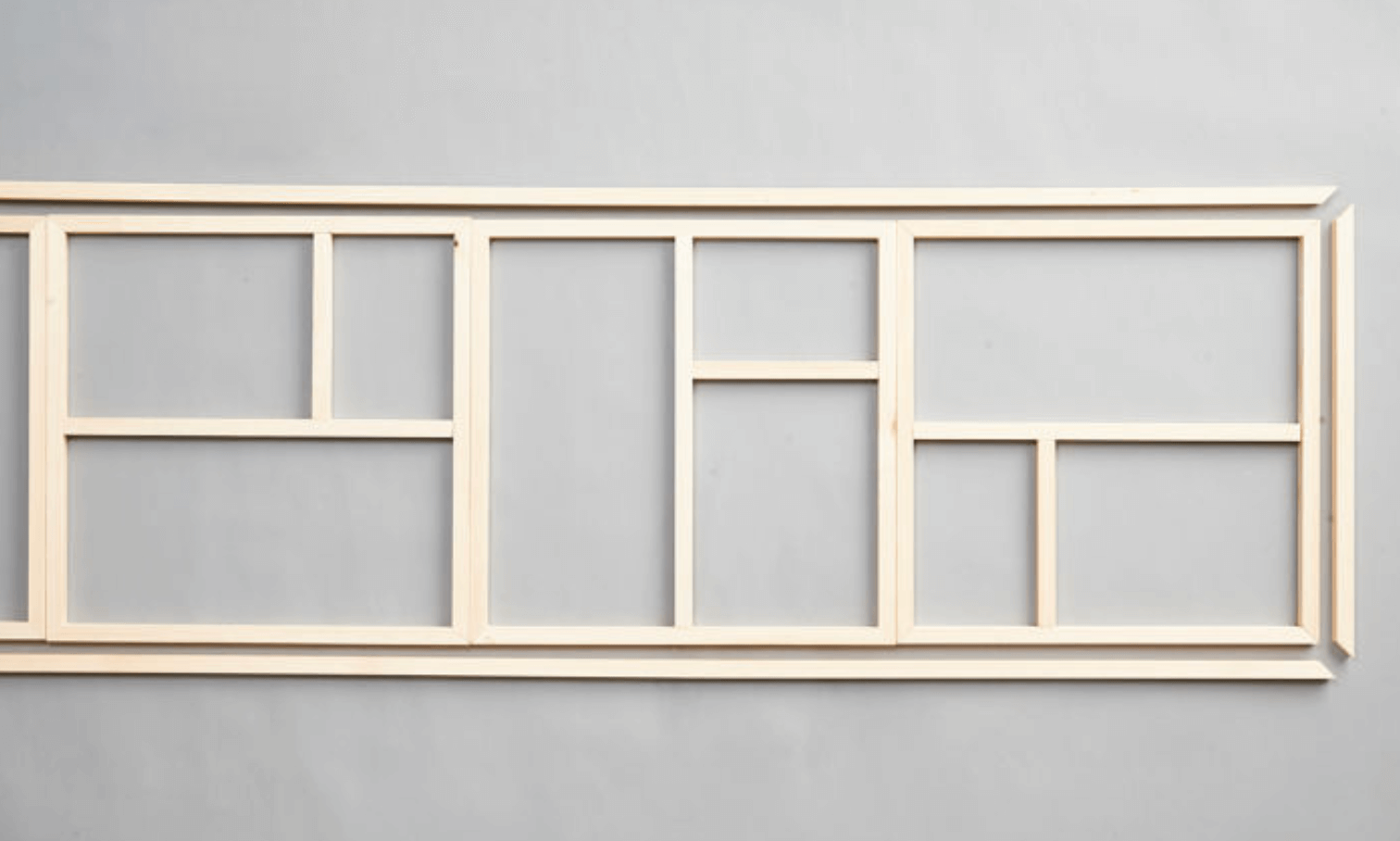 Liggande ljust träram med flera rektangulära fack mot grå bakgrund.