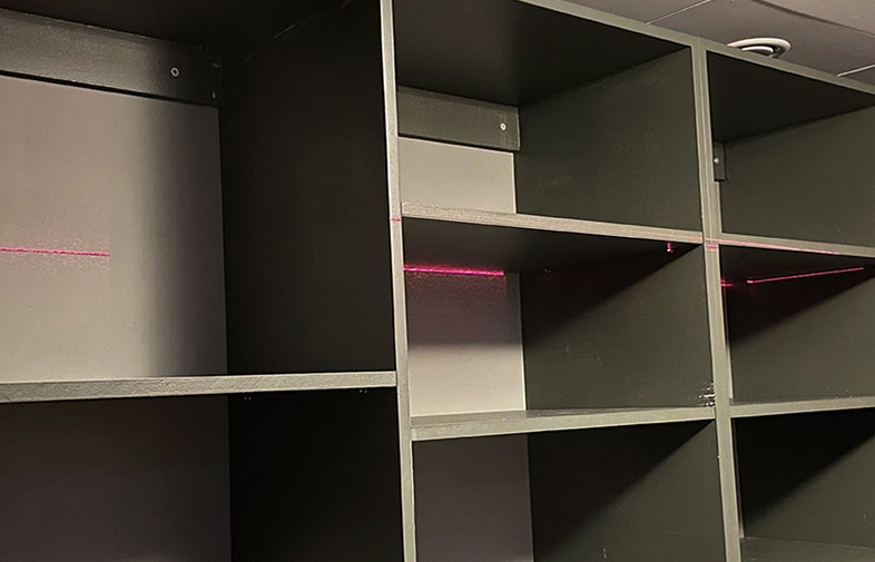 Tomma mörkgrå hyllfack i kubmönster med tunn rosa laserlinje genom mitten