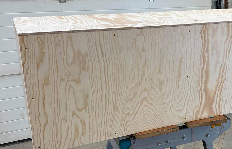 Omålad plywoodskiva med ljus träådring på snickarbock i verkstad