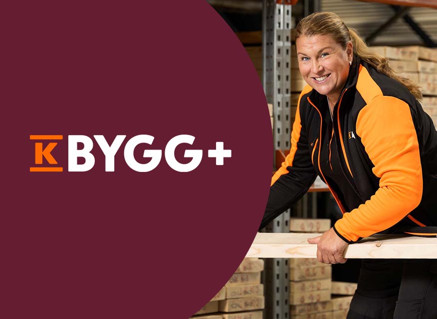 En person i svart och orange arbetskläder håller i en träregel i ett lager med staplade byggmaterial, bredvid en vinröd yta med texten "K BYGG+".