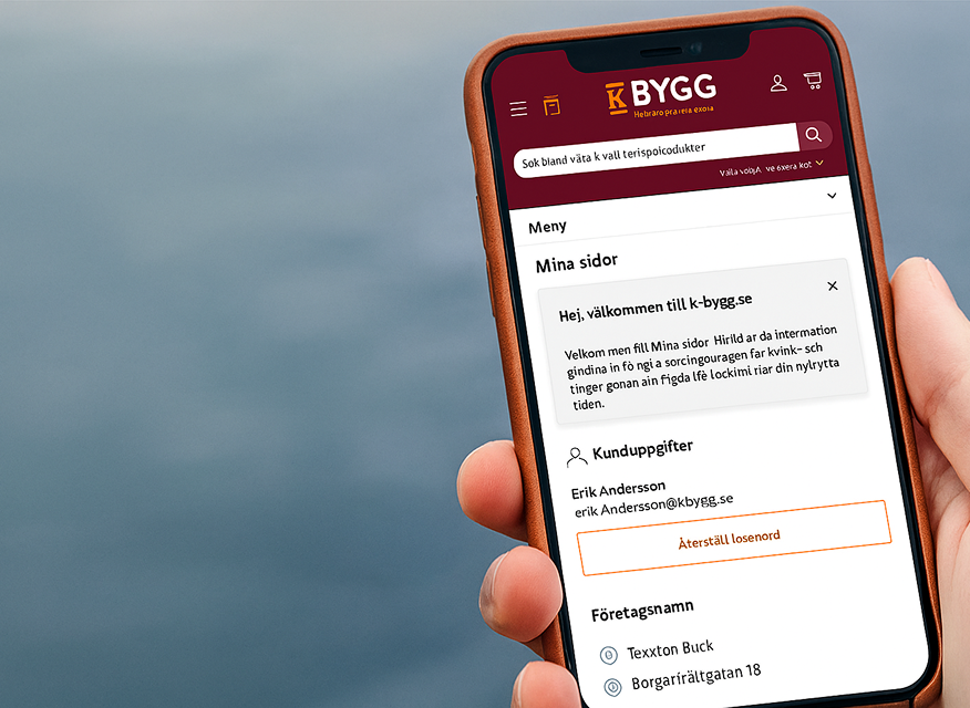 En person håller en mobiltelefon som visar K-Byggs "Mina sidor", där användaren kan se konto- och företagsuppgifter samt hantera sitt konto direkt i mobilen.