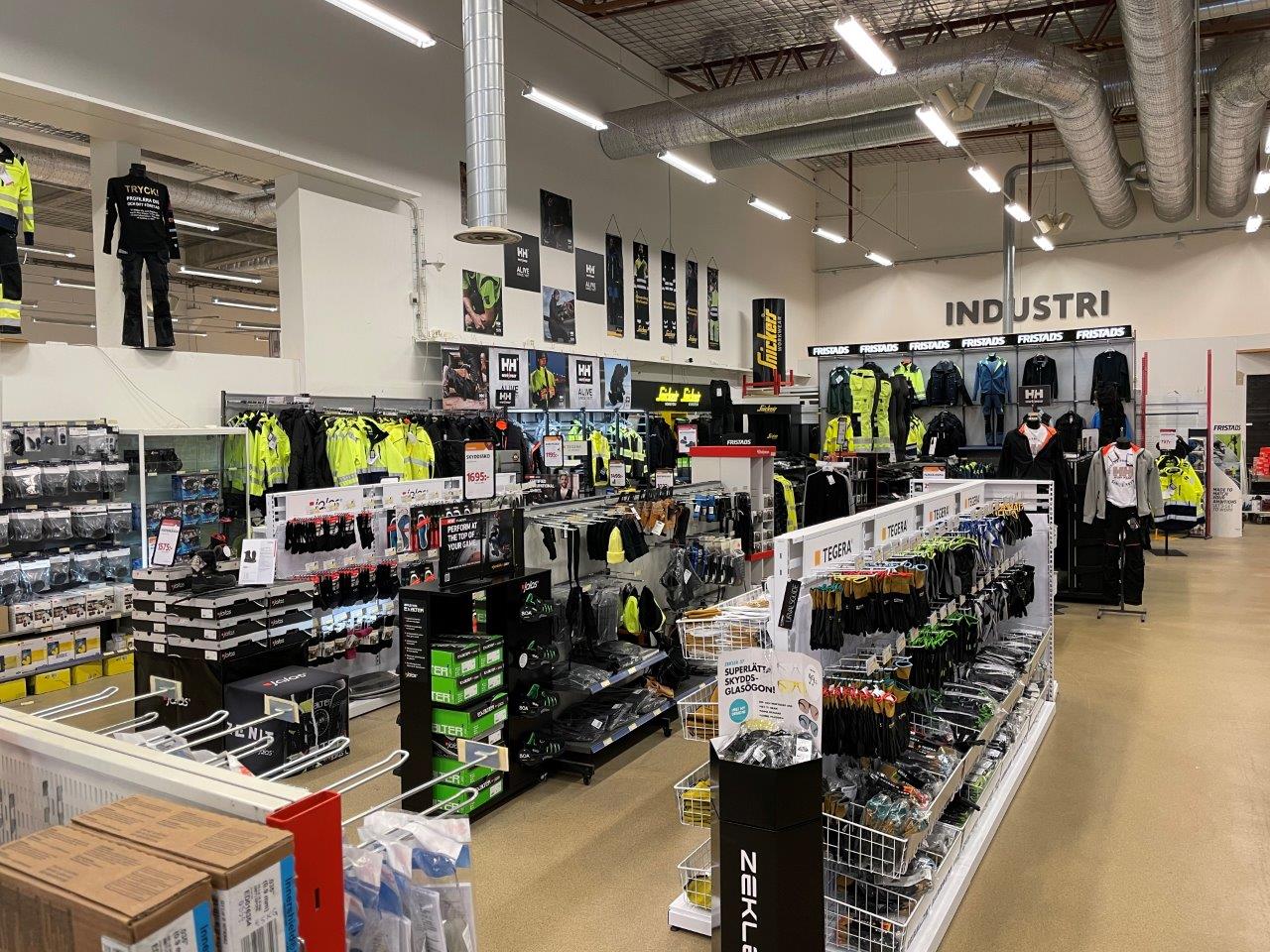 Stor butikslokal med hyllor av industrikläder, reflexjackor, handskar och skyddsglasögon