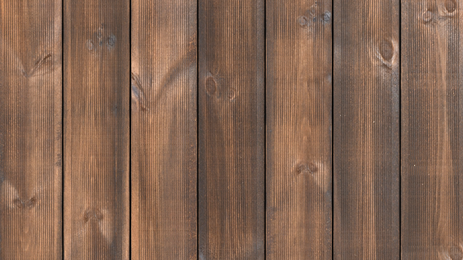 Närbild av vertikala bruna träpaneler som bakgrund, med synliga kvistar och ådring