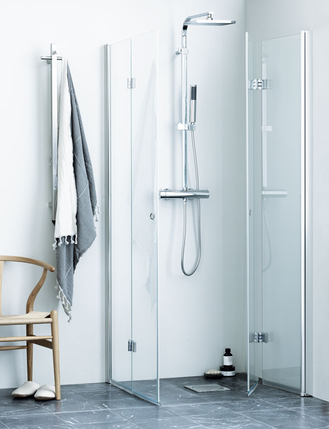 Minimalistisk glasdusch med kromad blandare, grå marmorgolv, hängande handdukar och stol