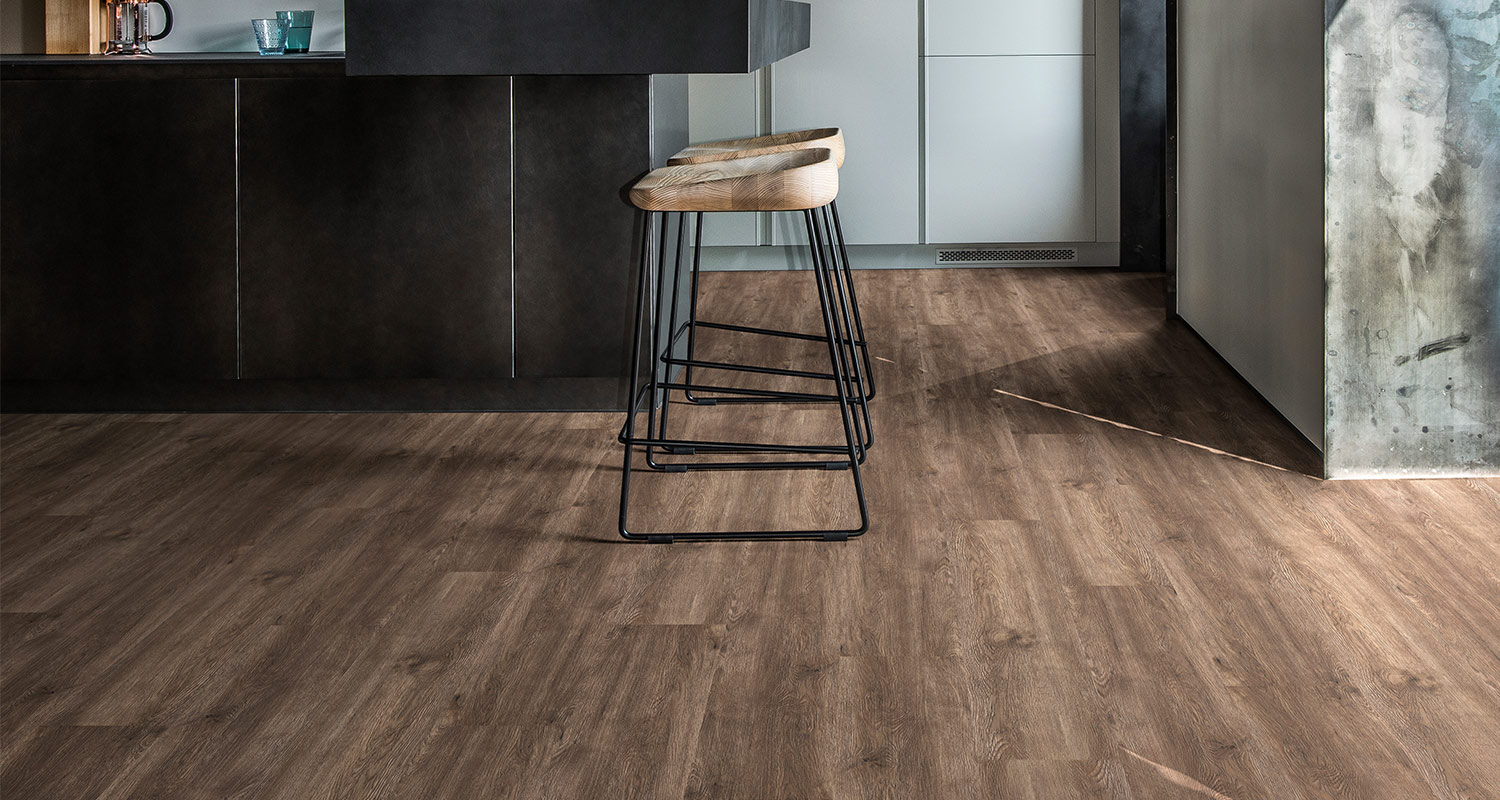 Modernt kök med svart köksö, två träbarstolar med svarta metallben på ljusbrunt trägolv