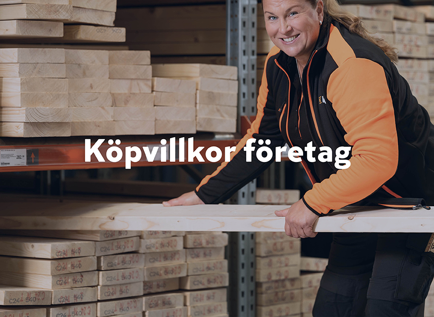 En person i ett lager eller en byggvarubutik som hanterar träplankor. I mitten av bilden står texten "Köpvillkor företag" tydligt, vilket antyder att bilden används för att illustrera köpvillkor riktade till företagskunder.