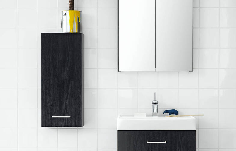 Minimalistiskt vitt kaklat badrum med svarta skåp, gul målarhink och blå hippo på handfat