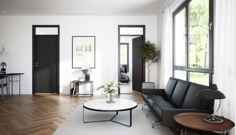 Ljust vardagsrum med svart soffa, runt marmorbord, mörka dörrar och stora fönster mot grönska.