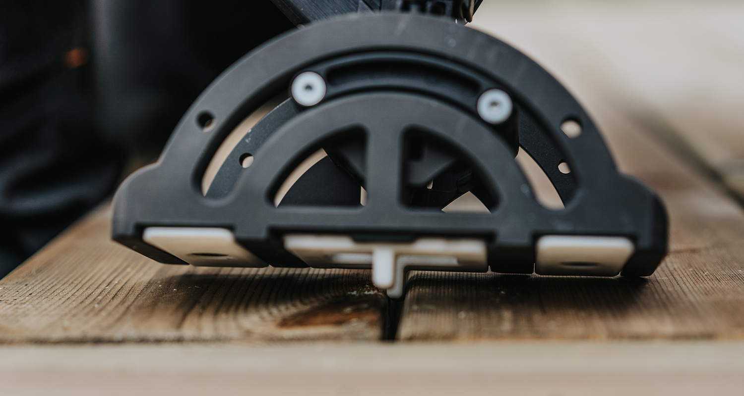 Svart plastverktyg på ljusbrunt trädäck som håller avstånd mellan två plankor