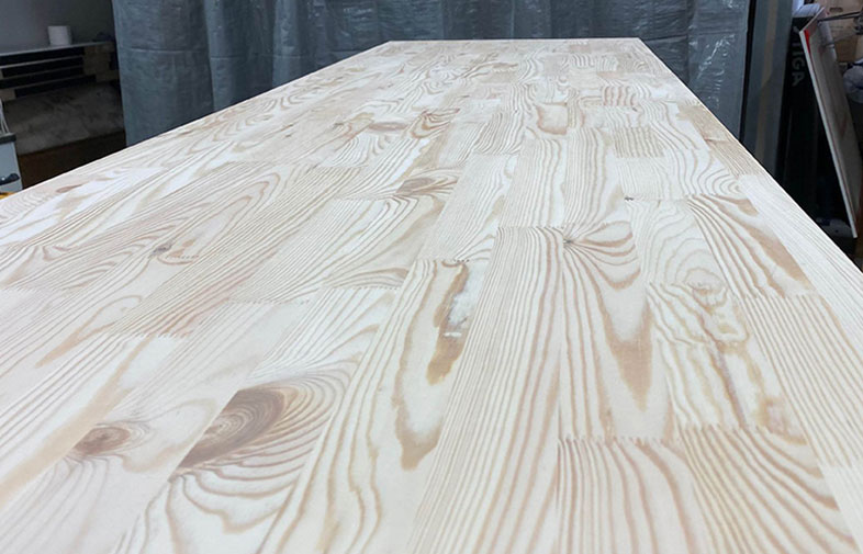 Ljus furubordsskiva med markanta ådringar i verkstadsmiljö