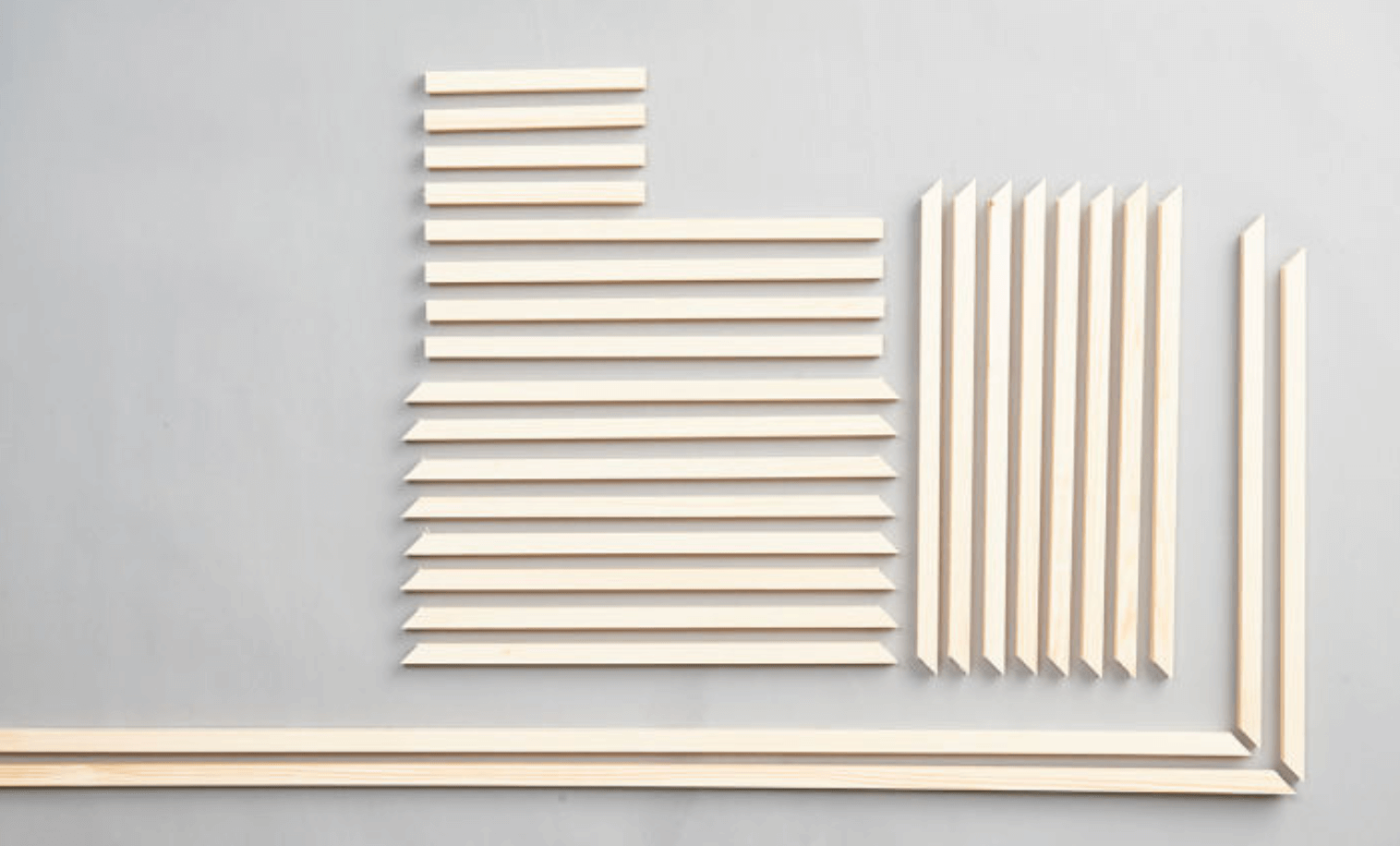 Ljus träremsor i olika längder arrangerade i rektanglar på grå bakgrund.
