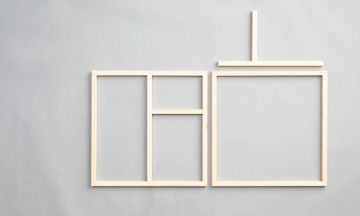 Två ljusa träramar med geometriska fack mot grå bakgrund