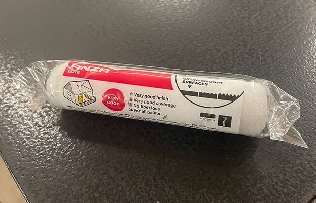 Vit skumfärgrulle i genomskinlig plastförpackning med röd ’Enza Elite’-etikett på svart bänk.