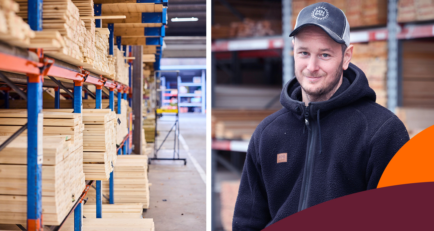 Trävaruhall med ljusa plankor på blå-oranga hyllor och man i svart fleecetröja med keps