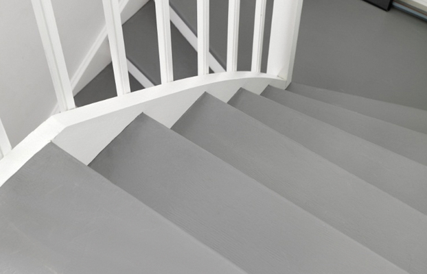 Vy uppifrån av grå trappa med vit spjälräcke mot vit vägg